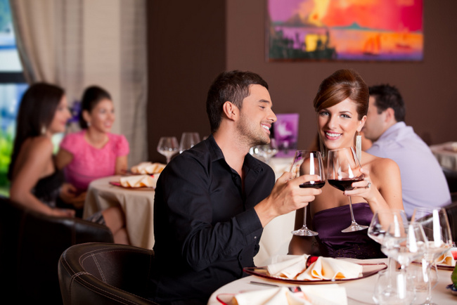 romantic young couple at restaurant table toasting