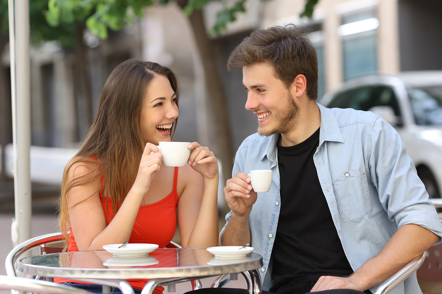 Happy couple or friends flirting talking and drinking in a restaurant terrace