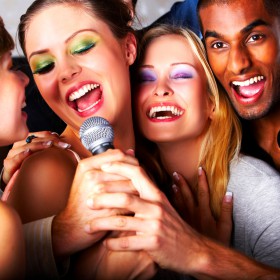 Five attractive friends singing together at a karaoke party